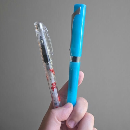 platinum preppy wa modern maki-e kingyo and ice blue twsbi swipe fountain pens held in hand in front of white wall